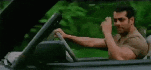 A Man Is Driving A Convertible Car And Making A Funny Face . GIF