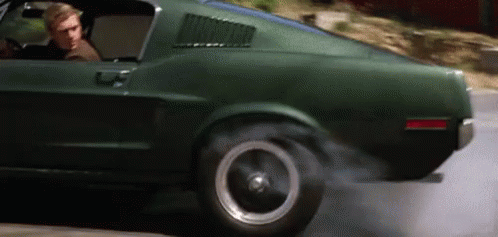 A Man Is Driving A Green Mustang On A Road GIF