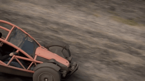 a man is driving a red and black buggy on a dirt road