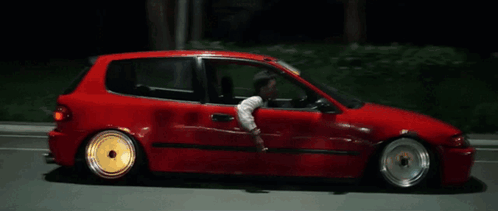 A Man Is Driving A Red Car At Night GIF