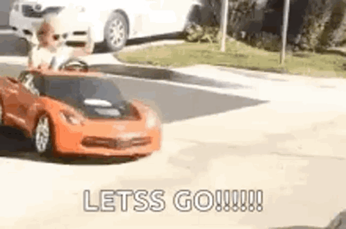 A Man Is Driving A Toy Car Down A Street . GIF