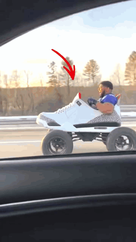 a man is driving a toy car that looks like a shoe with a red arrow pointing to it