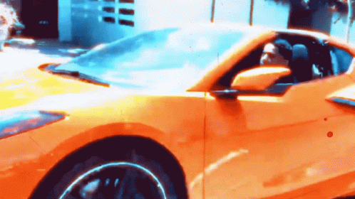 A Man Is Driving A Yellow Sports Car With A Blue Sky In The Background GIF
