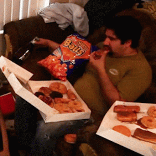 A Man Is Eating A Bag Of Cheetos Balls While Sitting On A Couch GIF