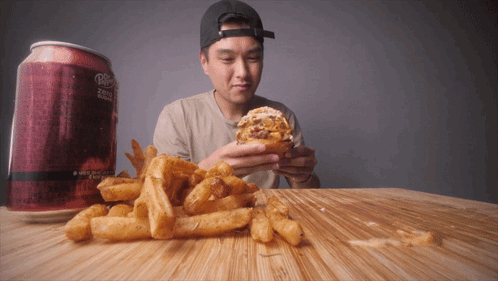 A Man Is Eating A Hamburger Next To A Can Of Diet Dr Pepper GIF
