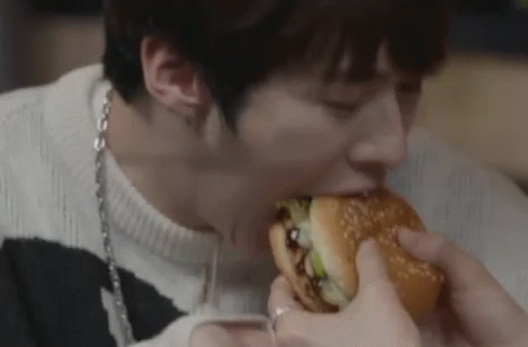 A Man Is Eating A Hamburger With His Eyes Closed . GIF