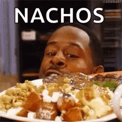 A Man Is Eating A Plate Of Food With Nachos Written On It . GIF