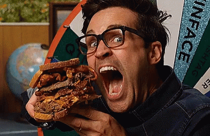 A Man Is Eating A Sandwich In Front Of A Sign That Says " Inface " GIF