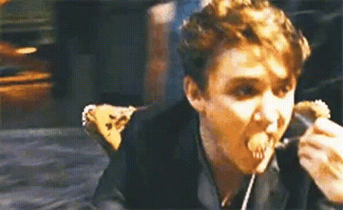 A Man Is Eating A Sandwich With A Fork And Spoon . GIF