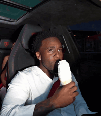 A Man Is Eating An Ice Cream Cone In The Back Seat Of A Car GIF