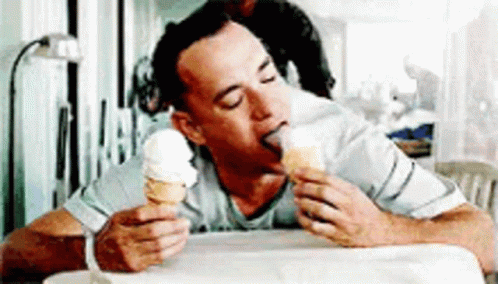 A Man Is Eating An Ice Cream Cone With His Tongue Sticking Out . GIF