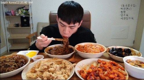 A Man Is Eating Noodles With Chopsticks At A Table With Bowls Of Food And A Time Of 12:35:40 Am GIF