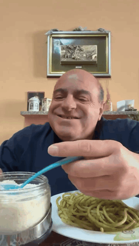 A Man Is Eating Spaghetti With A Spoon And Smiling GIF