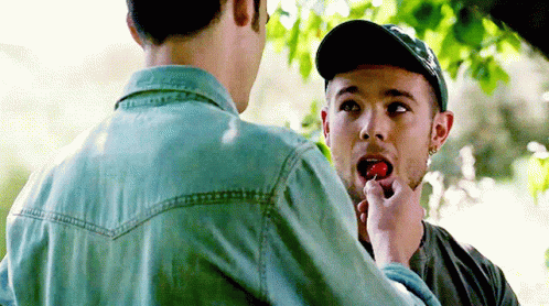 A Man Is Feeding Another Man A Strawberry GIF