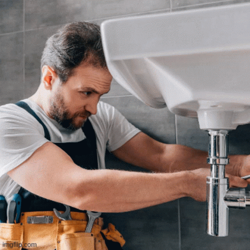 A Man Is Fixing A Sink Pipe With A Wrench GIF
