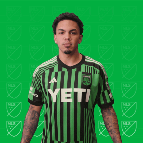 A Man Is Flexing His Muscles In A Green And Black Striped Shirt That Says Yeti GIF