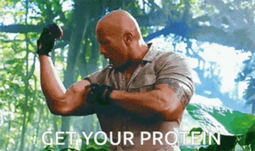 A Man Is Flexing His Muscles With The Words Get Your Protein Written Below Him GIF