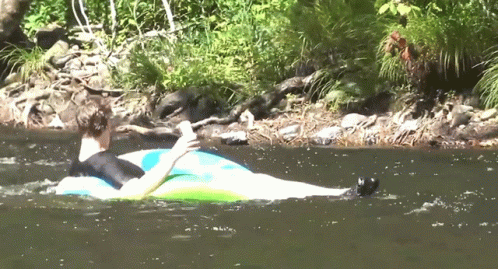 A Man Is Floating On A Tube In The Water GIF