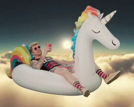 A Man Is Floating On An Inflatable Unicorn GIF