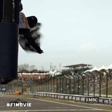 A Man Is Flying Through The Air At A Race Track With The #F1movie Written On The Bottom GIF