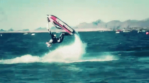 A Man Is Flying Through The Air While Riding A Wave On A Surfboard GIF