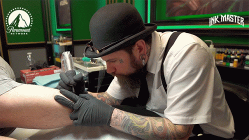 A Man Is Getting A Tattoo On Someone 'S Leg In A Paramount Network Tattoo Studio GIF