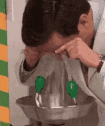A Man Is Getting His Eyes Rinsed With Water From A Faucet . GIF