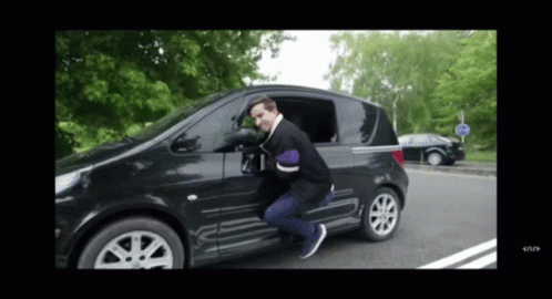A Man Is Getting Out Of A Black Car With A Stop Sign In The Background GIF