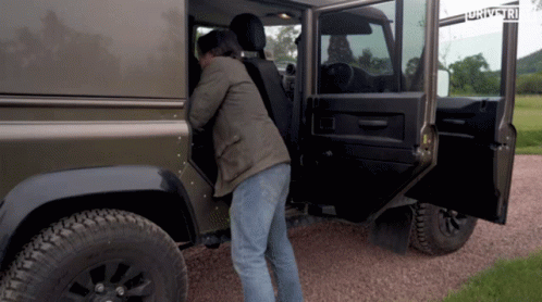 A Man Is Getting Out Of A Jeep That Has The Word Drive On The Side GIF