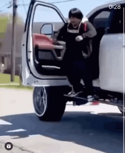 A Man Is Getting Out Of A White Truck With A Skateboard Attached To The Back Of It . GIF