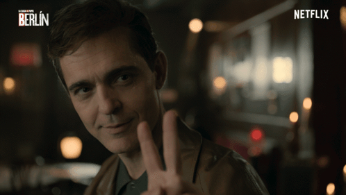 A Man Is Giving A Peace Sign In Front Of A Netflix Logo GIF