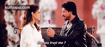 A Man Is Giving A Rose To A Woman Who Is Sitting On A Bench . GIF