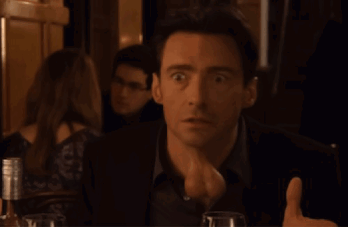 A Man Is Giving A Thumbs Up In A Dark Room GIF