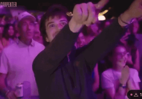 A Man Is Giving A Thumbs Up In Front Of A Crowd With The Word Carpenter On The Bottom Right GIF