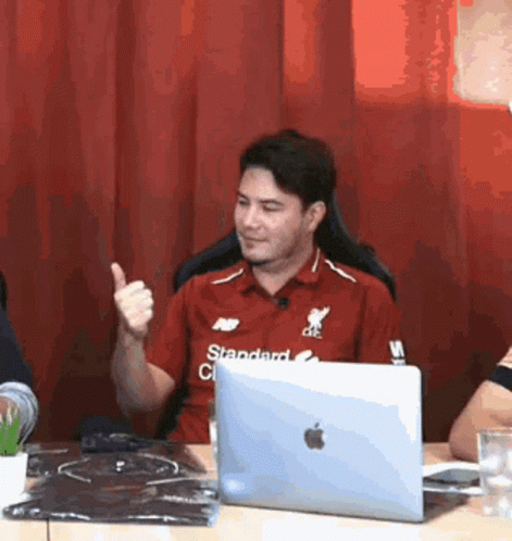 A Man Is Giving A Thumbs Up In Front Of A Laptop Computer . GIF