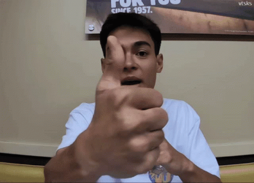 A Man Is Giving A Thumbs Up In Front Of A Poster That Says For You Since 1957 GIF