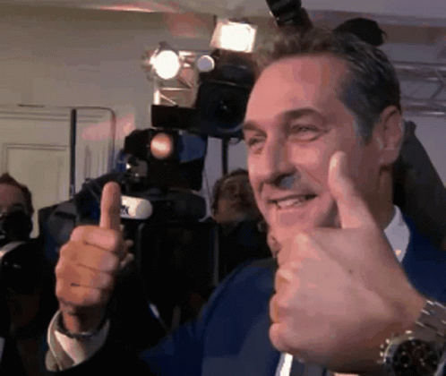 A Man Is Giving A Thumbs Up Sign In Front Of A Camera GIF