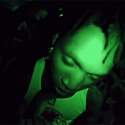 A Man Is Giving The Middle Finger In A Dark Room With A Green Light Behind Him GIF