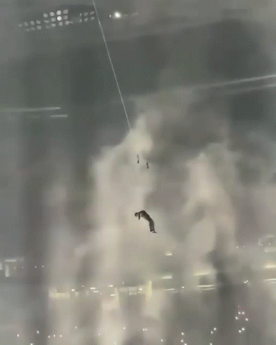A Man Is Hanging From A Rope In A Dark Room GIF
