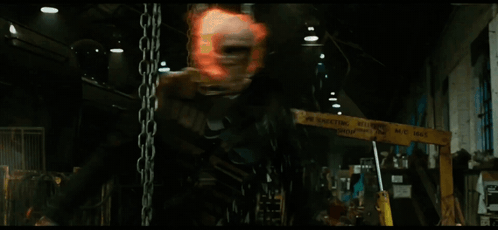 A Man Is Hanging From Chains In A Dark Room GIF