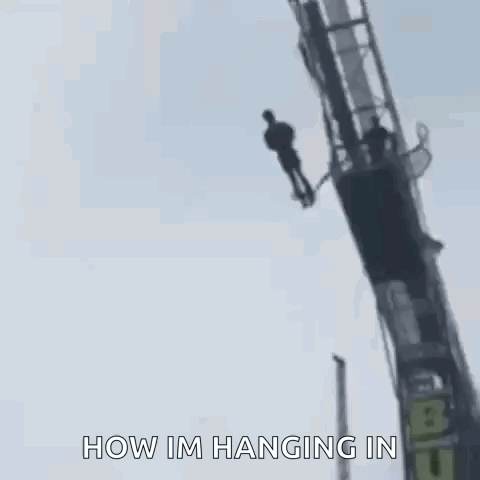 A Man Is Hanging Upside Down From A Bungee Ride . GIF