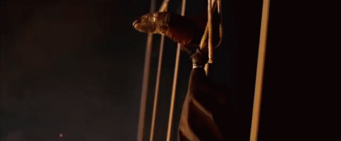 A Man Is Hanging Upside Down With A Golden Mask On His Face . GIF