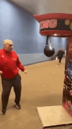 A Man Is Hitting A Punching Bag In A Boxing Machine GIF