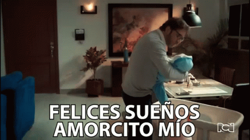 A Man Is Holding A Baby In A Living Room And The Words Felices Suenos Amorcito Mio Are Above Him GIF