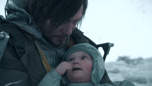 A Man Is Holding A Baby In His Arms And The Baby Is Wearing A Grey Jacket With The Word Columbia On It GIF