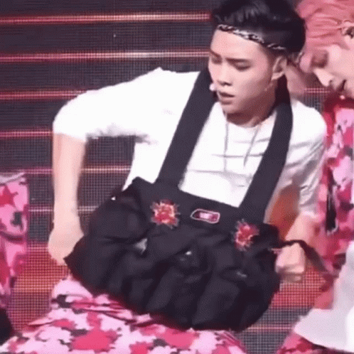 A Man Is Holding A Bag On His Stomach While Dancing On A Stage . GIF