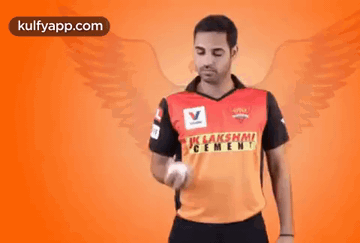 A Man Is Holding A Ball In His Hand And Wearing A Shirt That Says ' Lakshmi Cement ' On It . GIF