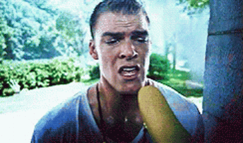 A Man Is Holding A Banana In His Mouth GIF