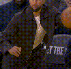 A Man Is Holding A Basketball While Sitting In The Stands . GIF