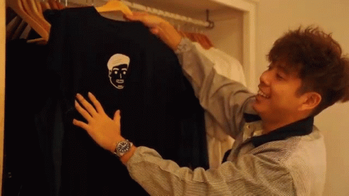a man is holding a black shirt with a face on it